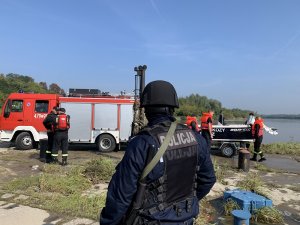 Policjanci, strażacy oraz ratownicy medyczni biorący udział w ćwiczeniach. Osoby na zdjęciach wykonują m.in. czynności przy wypadku drogowym, poszukiwania w rejonie rzeki, zabezpieczanie obiektu MOW Zawichost.