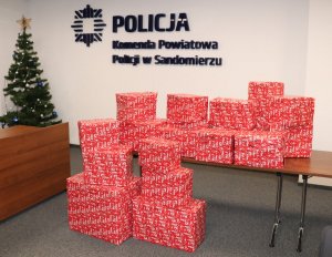 Policjanci i pracownicy cywilny przy zapakowanych prezentach zebranych w ramach akcji szlachetna paczka.